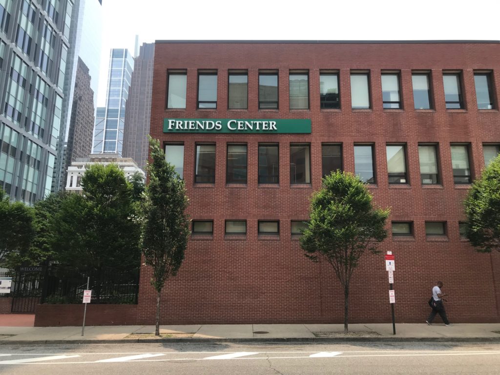 Photo of Friends Center's 1501 Cherry Street building, with a new sign saying "Friends Center" in white letters on a green background on the brick wall.